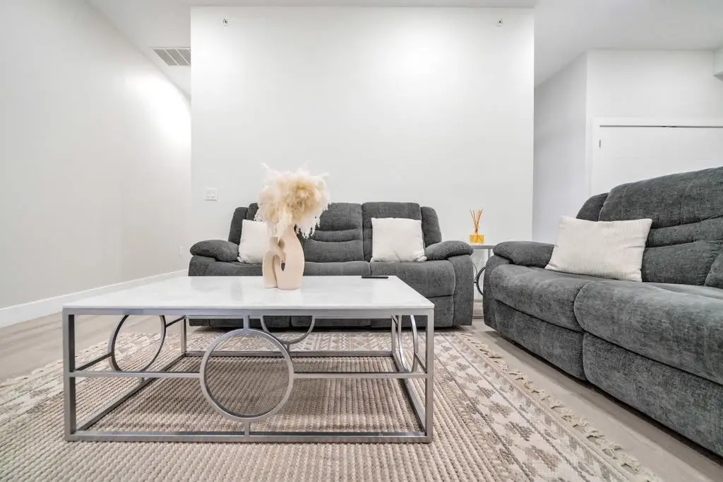 Living area with grey recliner sofas and a silver-framed coffee table, Residence 106