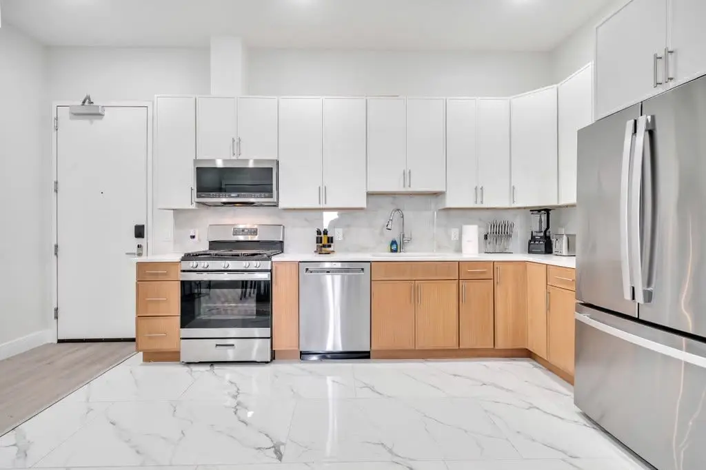 Kitchen with white upper cabinets, light-wood lower cabinets and stainless appliances, Residence 106