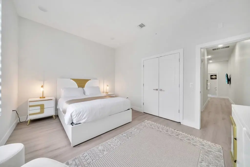 Bedroom with white bed, two bedside tables and a double closet door, Residence 106