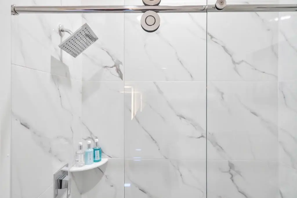 Shower with white marble-look tile and sliding glass door, Residence 106