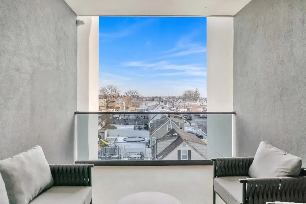 Terrace seating area with glass railing and a view over nearby buildings, Residence 106