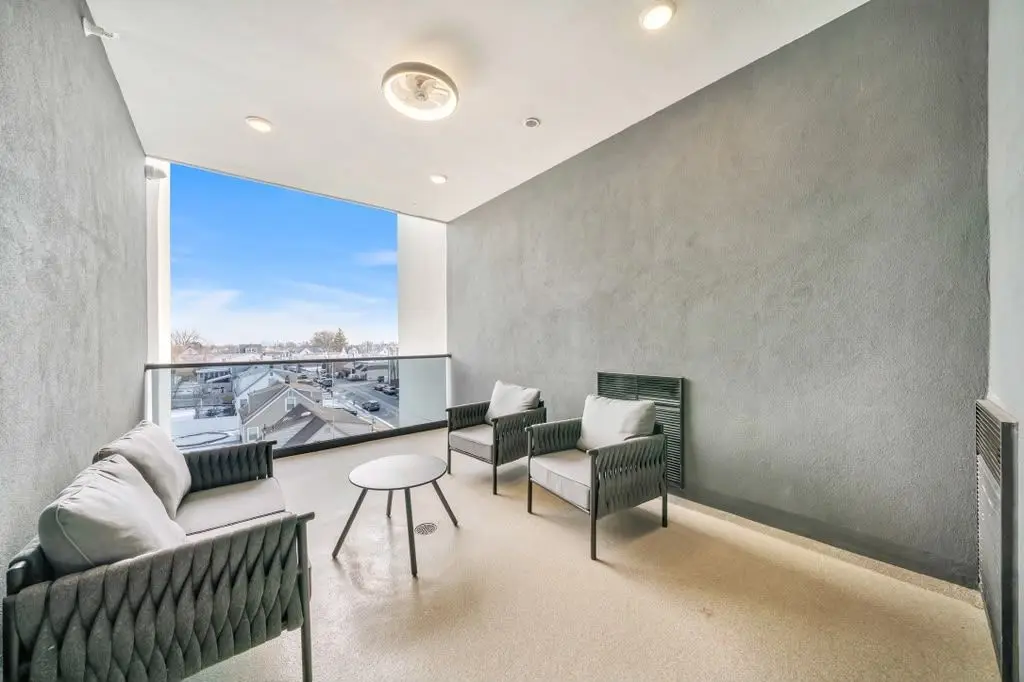 Enclosed terrace with grey textured wall, outdoor seating and a large window with glass railing, Residence 106