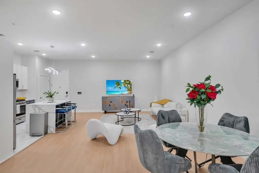 Open-plan living area with round glass dining table, grey chairs and white sculptural chairs, Residence 304