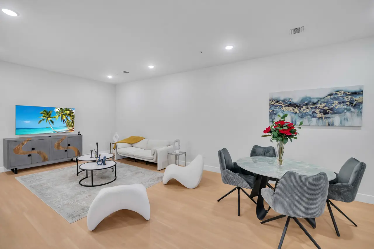 Living area with TV console, white sculptural chairs and a round glass dining table with red roses, Residence 304