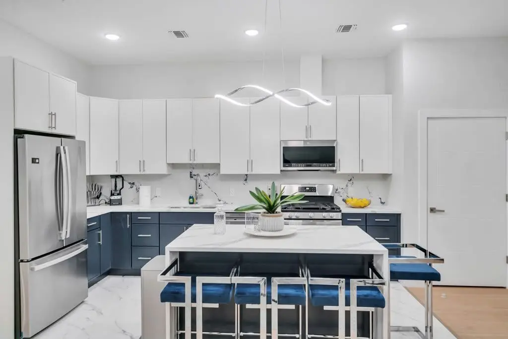 Kitchen with white cabinets, navy lower cabinets and an island with navy bar stools, Residence 304