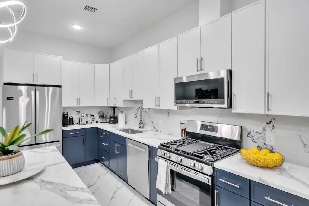 Kitchen with navy lower cabinets, white upper cabinets, marble-look counter and a yellow bowl, Residence 304