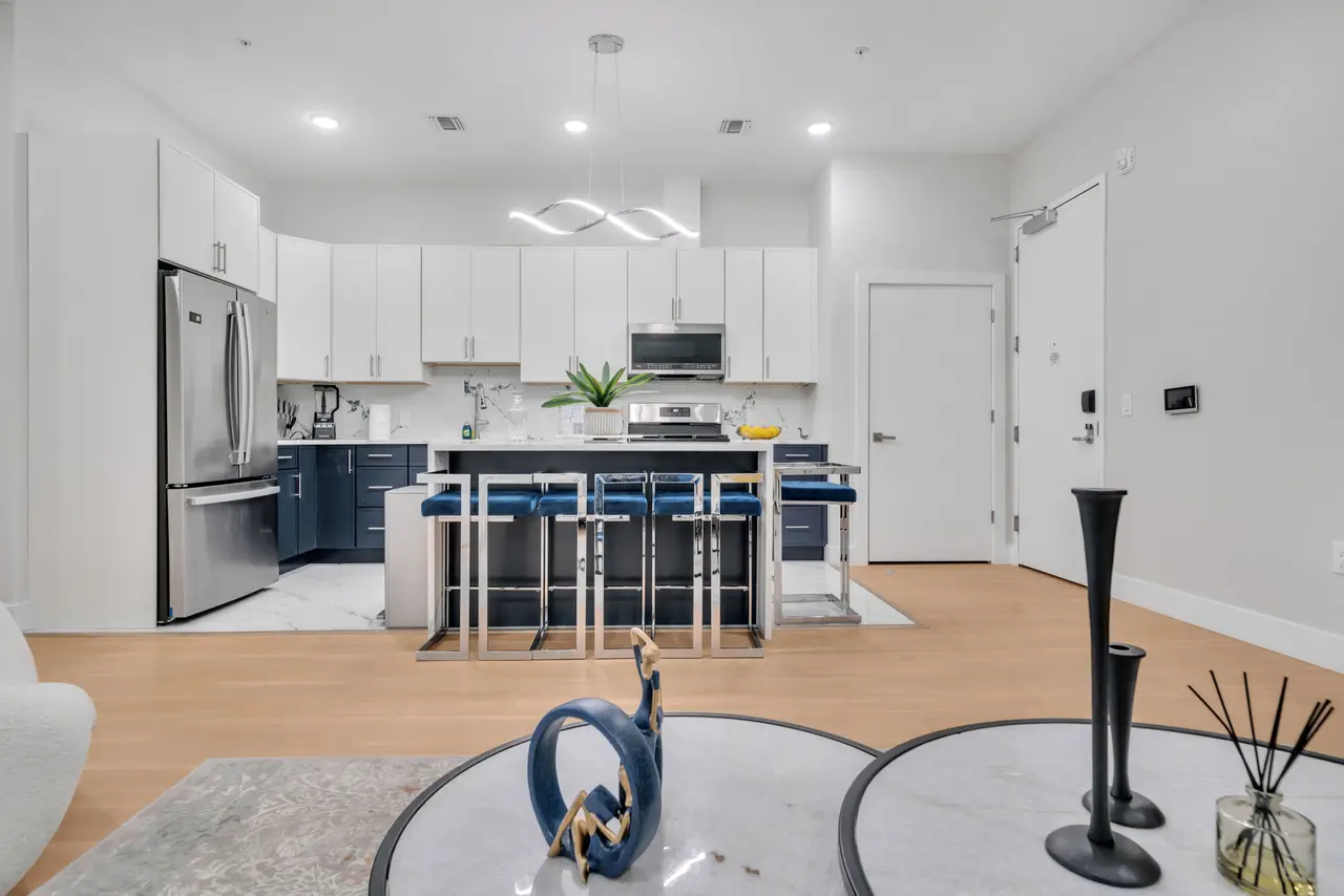 Kitchen island with navy stools, open to a living area with black decorative vases