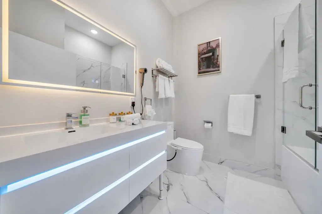 Bathroom with floating white vanity with LED strip, lit mirror and glass shower, Residence 304