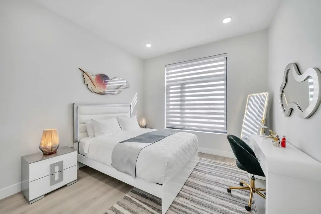 Bedroom with white bed, nightstand and desk, Residence 402