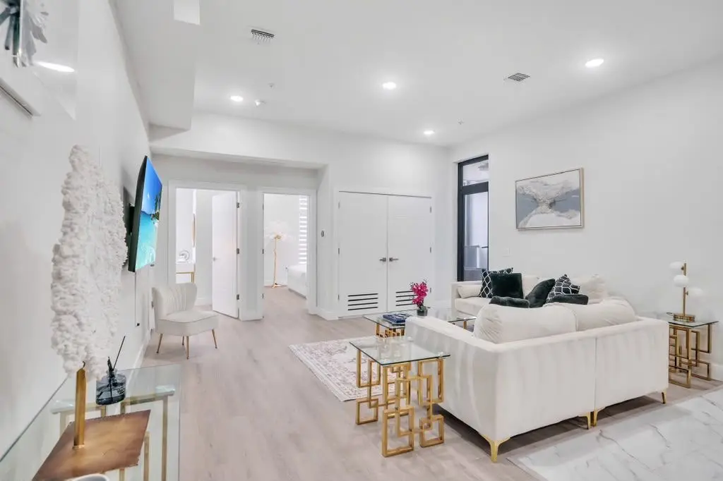 Living room with cream sofa, gold coffee table and wall-mounted TV, Residence 407