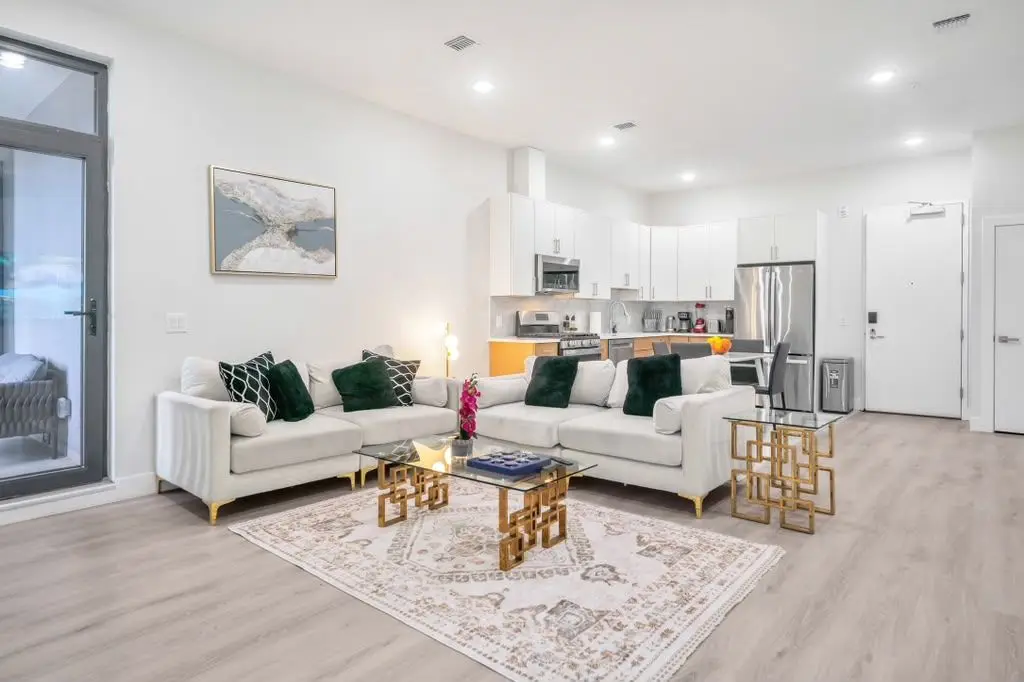 Open-plan living room with cream sofas, patterned rug and kitchen behind, Residence 407
