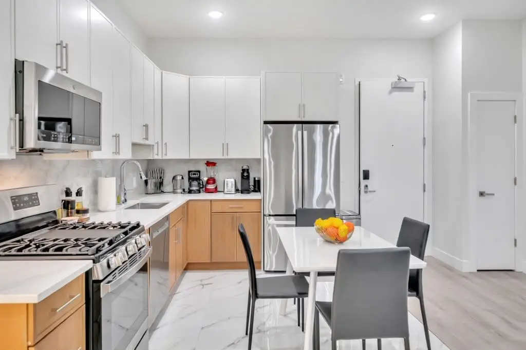Kitchen with white cabinets, light-wood lower cabinets, stainless appliances and a small dining table, Residence 407