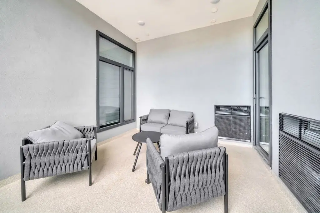 Enclosed terrace with grey woven armchairs, side tables and large dark-framed windows, Residence 407