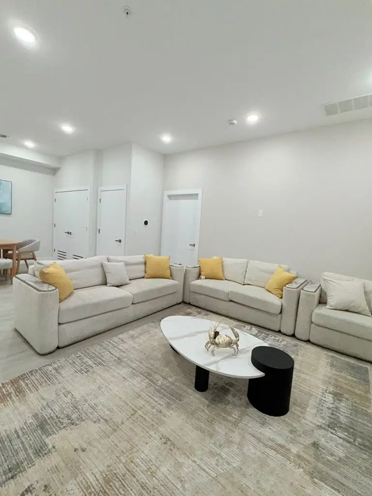Living room with cream sofas with yellow cushions and an oval coffee table, Residence 409