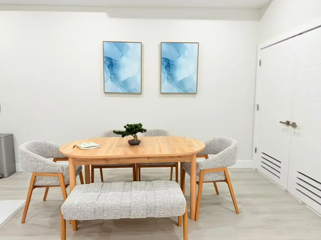Oval wooden dining table with bench and two blue abstract prints, Residence 409