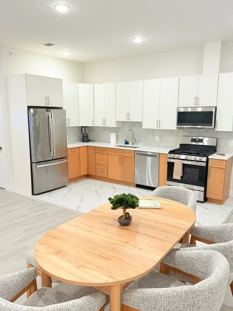 Kitchen with white cabinets, stainless appliances and an oval wooden table, Residence 409
