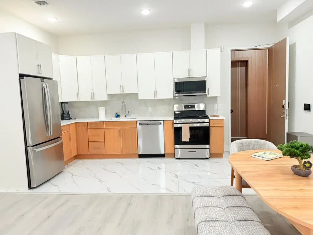 Kitchen with white cabinets, light-wood lower cabinets, stainless appliances and marble-look floor, Residence 409