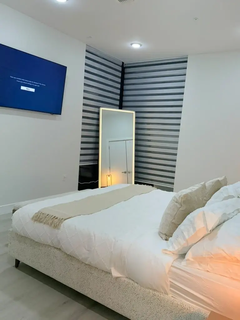 Bedroom with a large bed, standing mirror and wall-mounted TV, Residence 409