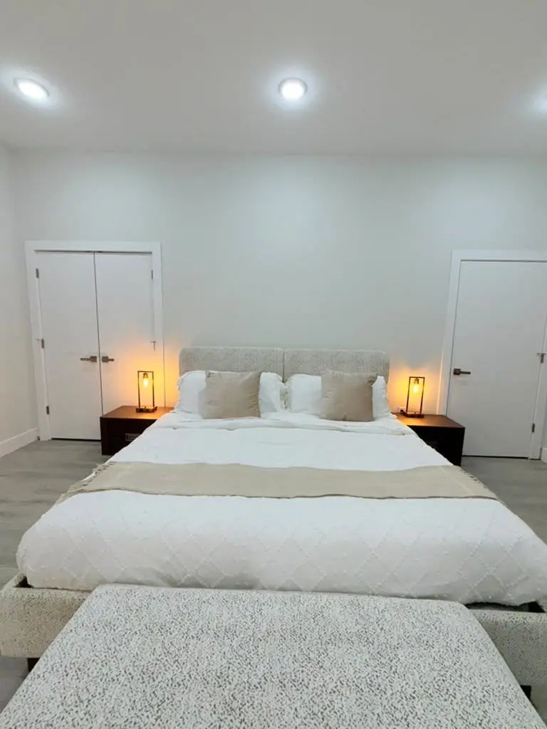 Bedroom with a large bed, upholstered bench, bedside lamps and a double closet door, Residence 409