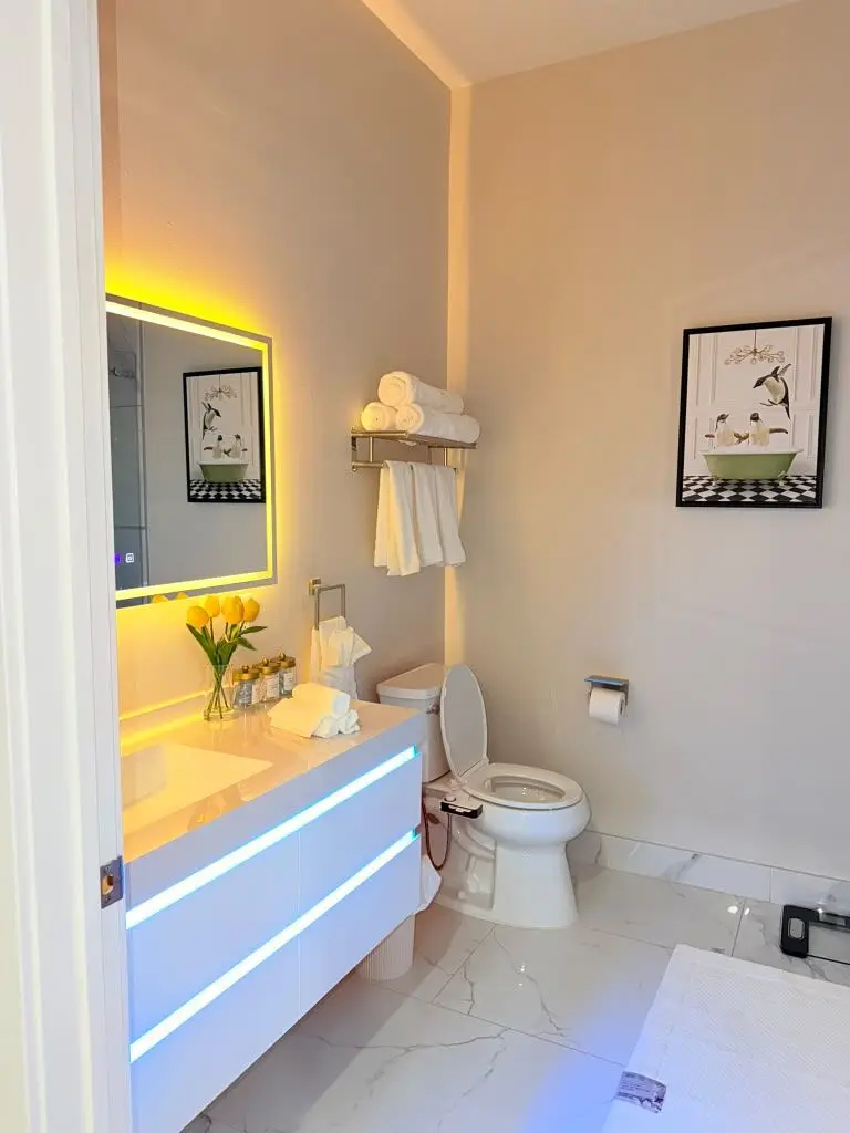 Bathroom with floating vanity, lit mirror and yellow-toned lighting, Residence 409