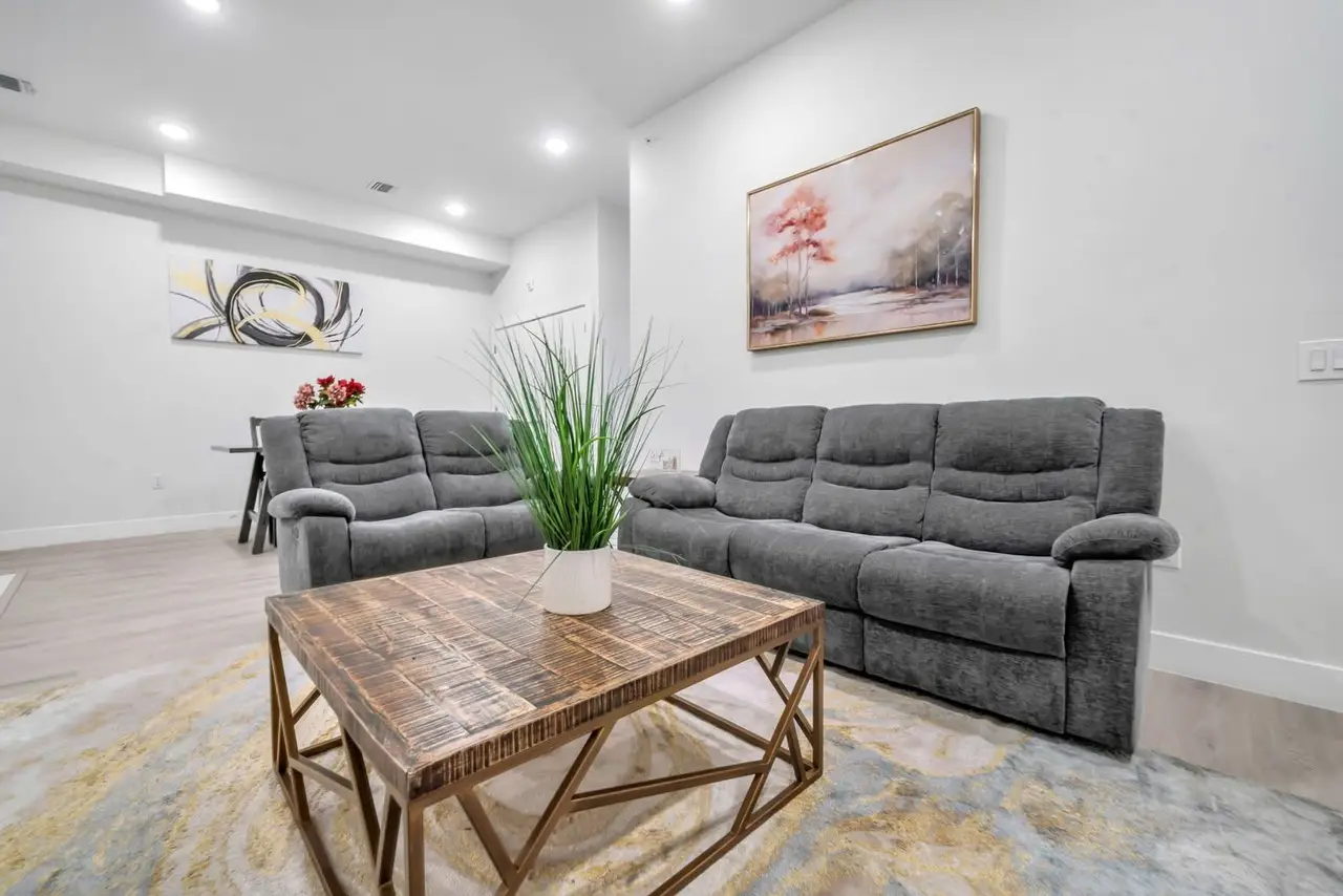 Living room with grey reclining sofas, wooden coffee table and a potted plant, Residence 412