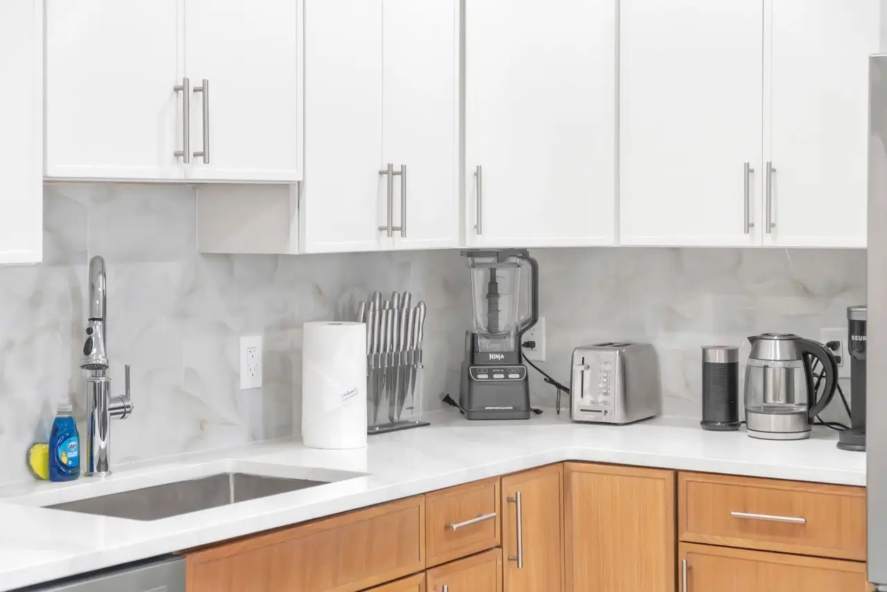Kitchen sink corner with white cabinets and light-wood lower cabinets, Residence 412