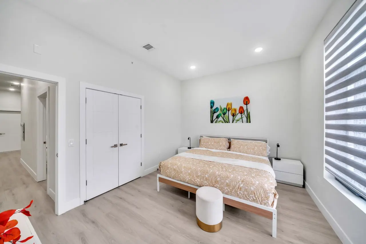 Bedroom with bed, upholstered bench, double closet door and floral wall art, Residence 412