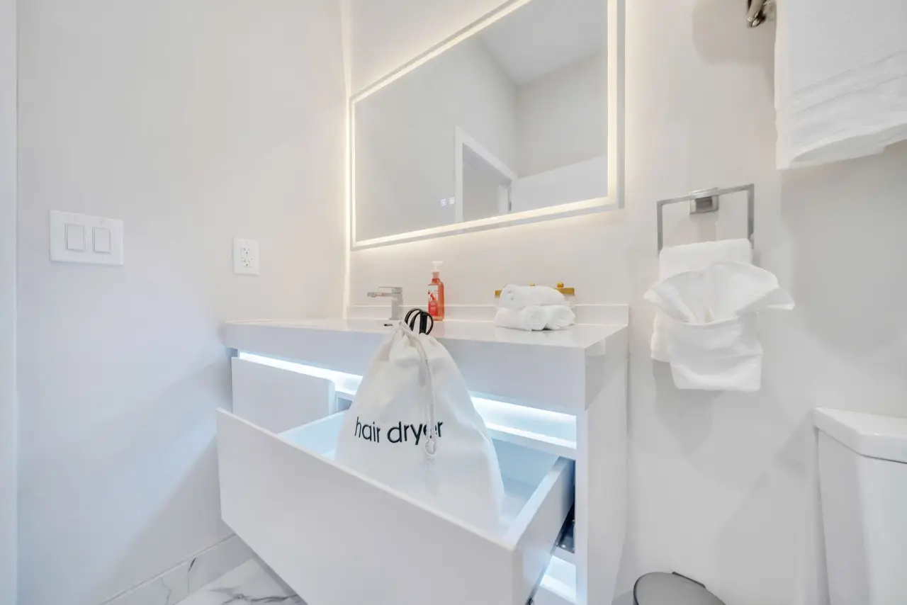 Bathroom vanity with open drawer, lit mirror and towels, Residence 412
