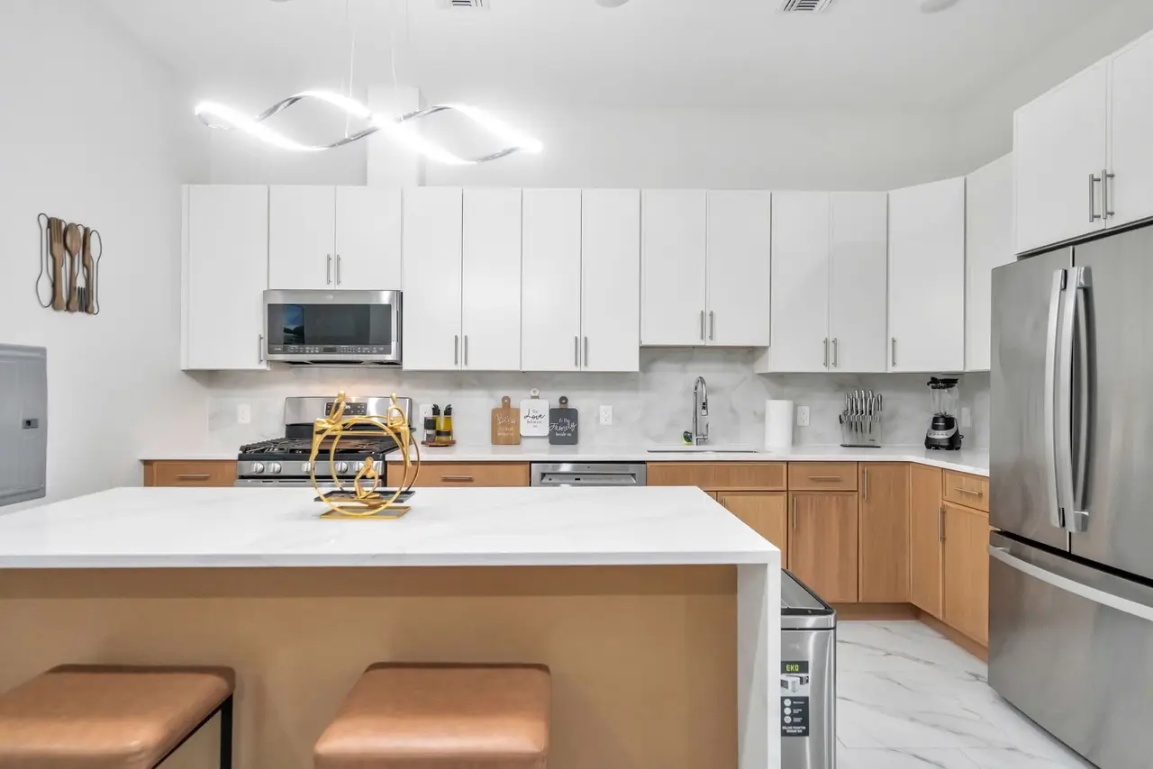 Kitchen with white cabinets, light-wood island with tan stools and stainless appliances, Residence 414