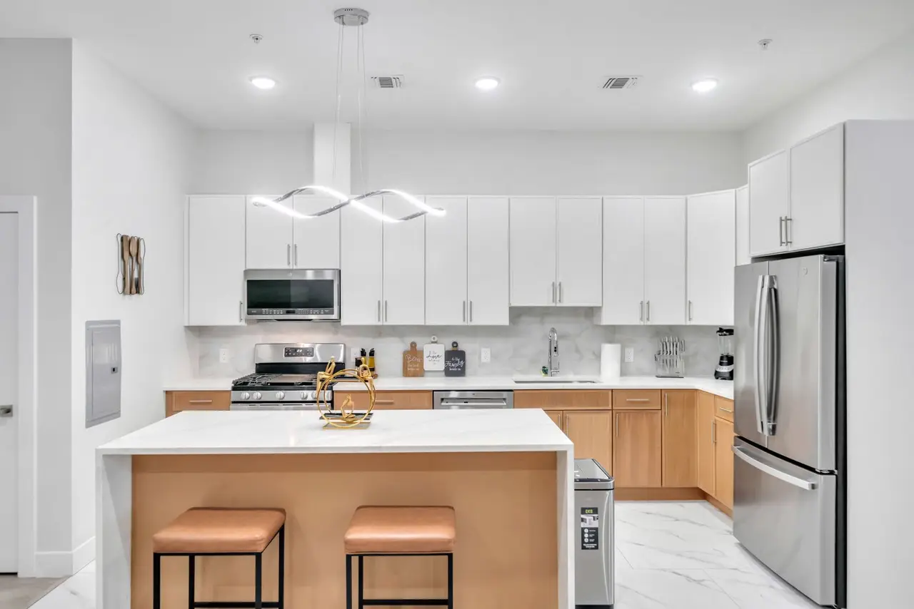 Kitchen with white cabinets, light-wood island and tan stools, Residence 414