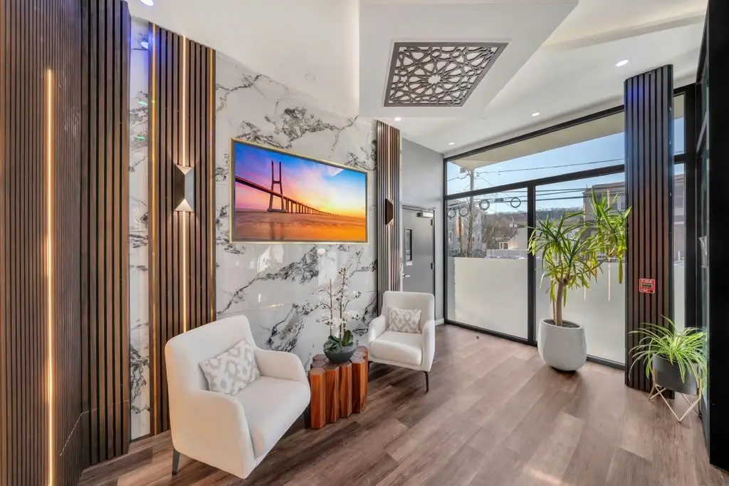 Building lobby seating area with white armchairs, TV and a window